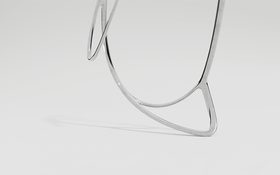 DIN - dancing in norms – close-up of a delicate dancing figure made of glossy metal wire against a light grey background
