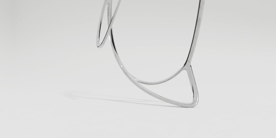 close-up of a sweeping, chrome-colored wire frame reminiscent of an abstracted chair shape