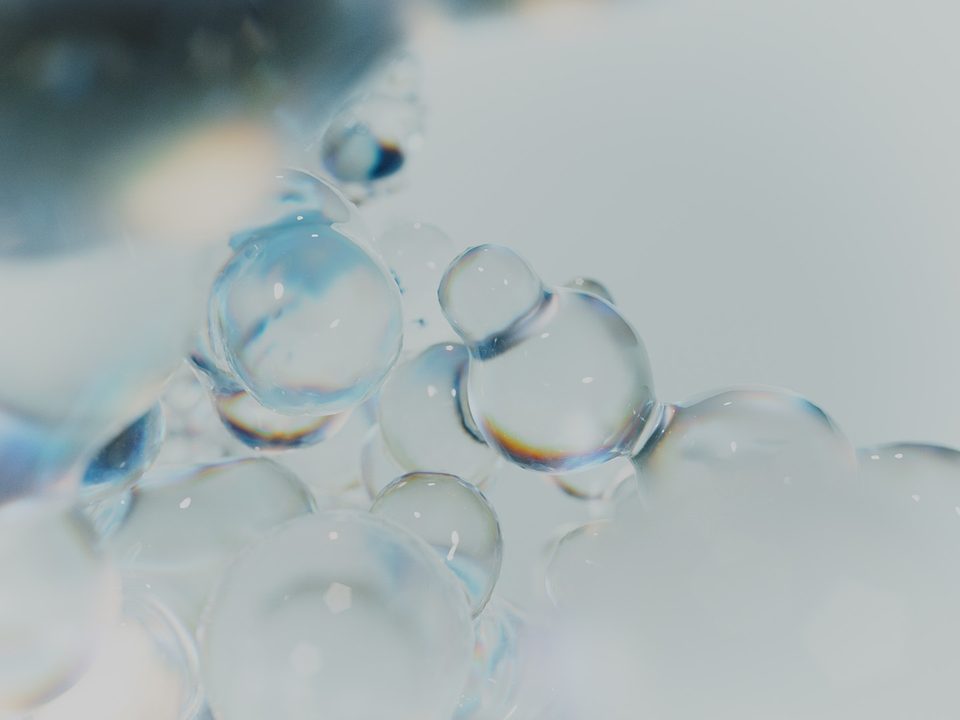 close-up of several transparent bubble shapes merging into one another against a light grey background